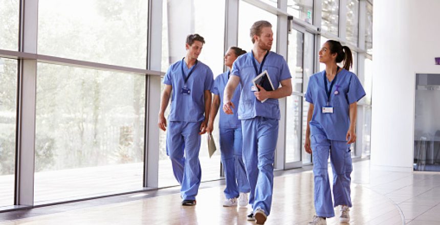 Four healthcare workers in scrubs walking in corridor